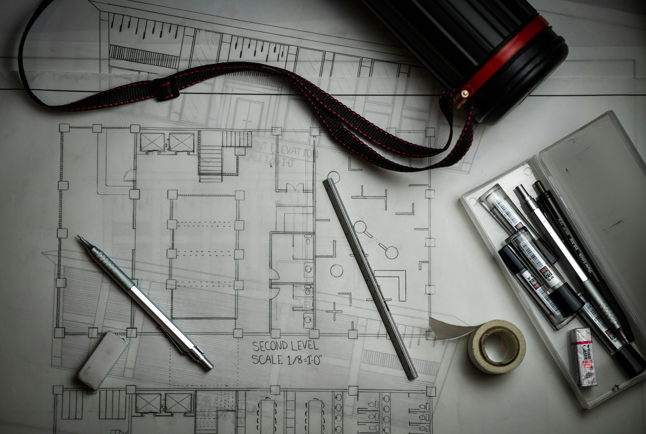 Printed architectural plans with a scale ruler and pencils